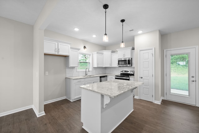 kitchen with white cabinetry, hanging light fixtures, a kitchen island, and stainless steel appliances