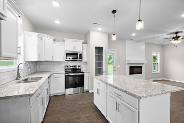 kitchen featuring white cabinets, appliances with stainless steel finishes, pendant lighting, and sink