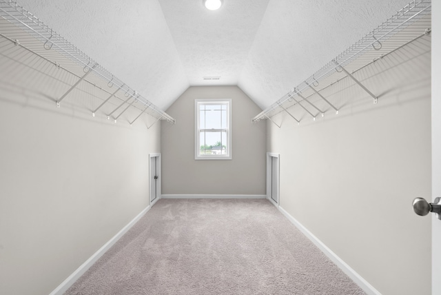 spacious closet with carpet flooring and vaulted ceiling