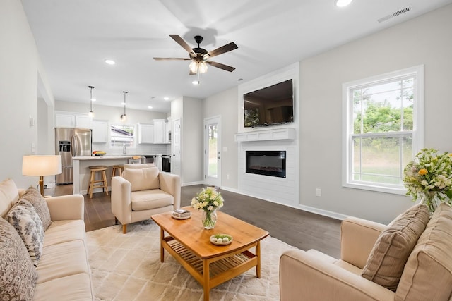 living room with light wood-type flooring, ceiling fan, and sink