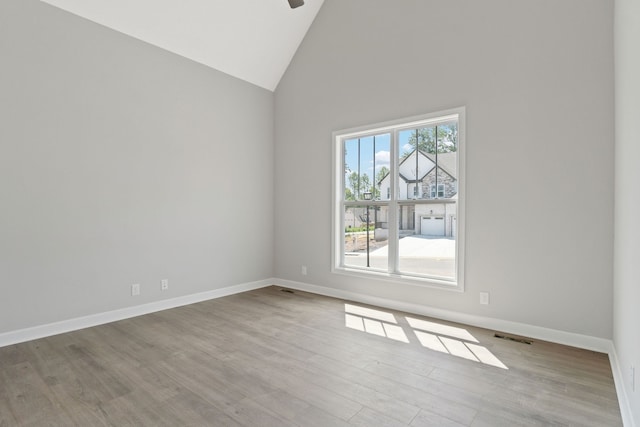 spare room with light hardwood / wood-style floors and high vaulted ceiling