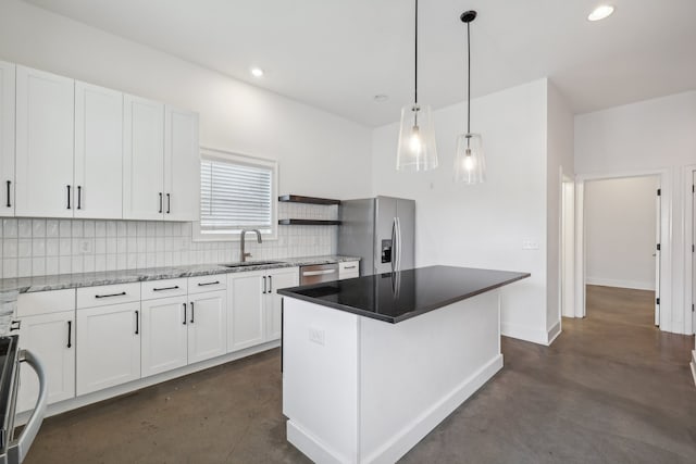 kitchen featuring hanging light fixtures, stainless steel appliances, sink, a center island, and white cabinetry