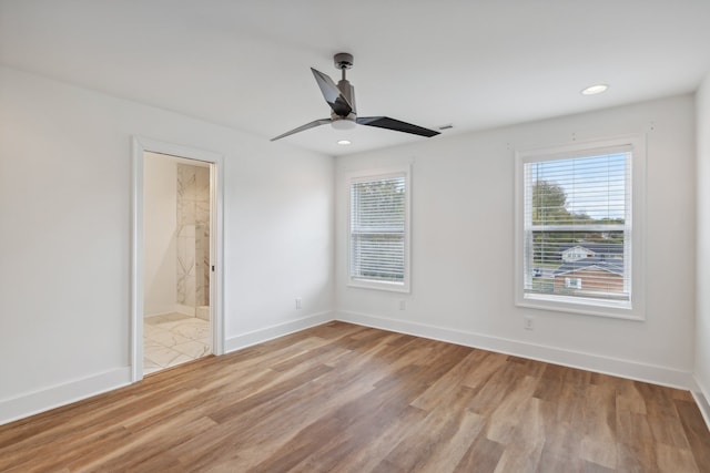 unfurnished bedroom with connected bathroom, light hardwood / wood-style flooring, multiple windows, and ceiling fan