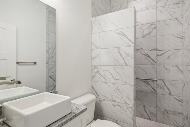 bathroom featuring vanity, toilet, and tiled shower