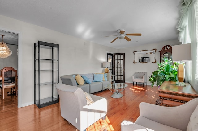 living room featuring light wood-type flooring and ceiling fan with notable chandelier