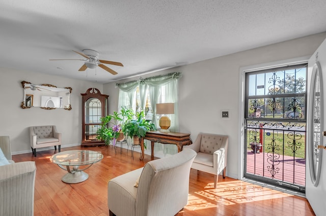 living room with ceiling fan, wood-type flooring, and a textured ceiling