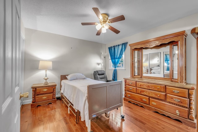 bedroom featuring a textured ceiling, wood-type flooring, and ceiling fan