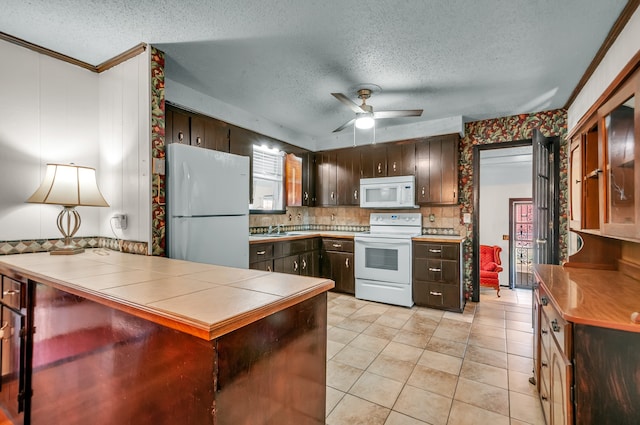 kitchen with ceiling fan, ornamental molding, dark brown cabinetry, sink, and white appliances