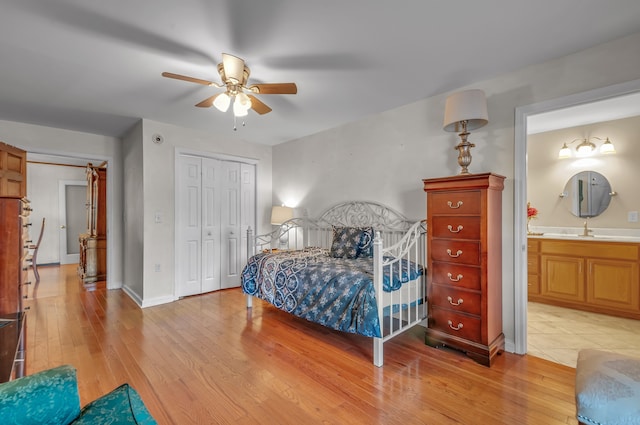 bedroom featuring ensuite bath, sink, light wood-type flooring, and ceiling fan