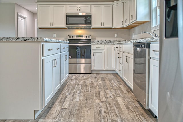 10309 Goff Ridge Rd, Baxter, TN 38544 - kitchen with stainless steel appliances, light wood-style floors, light stone countertops, and white cabinetry