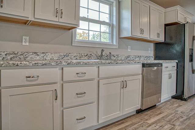 kitchen with white cabinetry, stainless steel appliances, and light hardwood / wood-style flooring