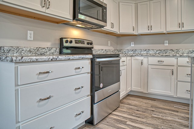 kitchen with light stone counters, stainless steel appliances, light hardwood / wood-style flooring, and white cabinets