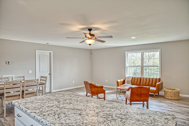 interior space with light hardwood / wood-style floors, white cabinetry, light stone countertops, and ceiling fan