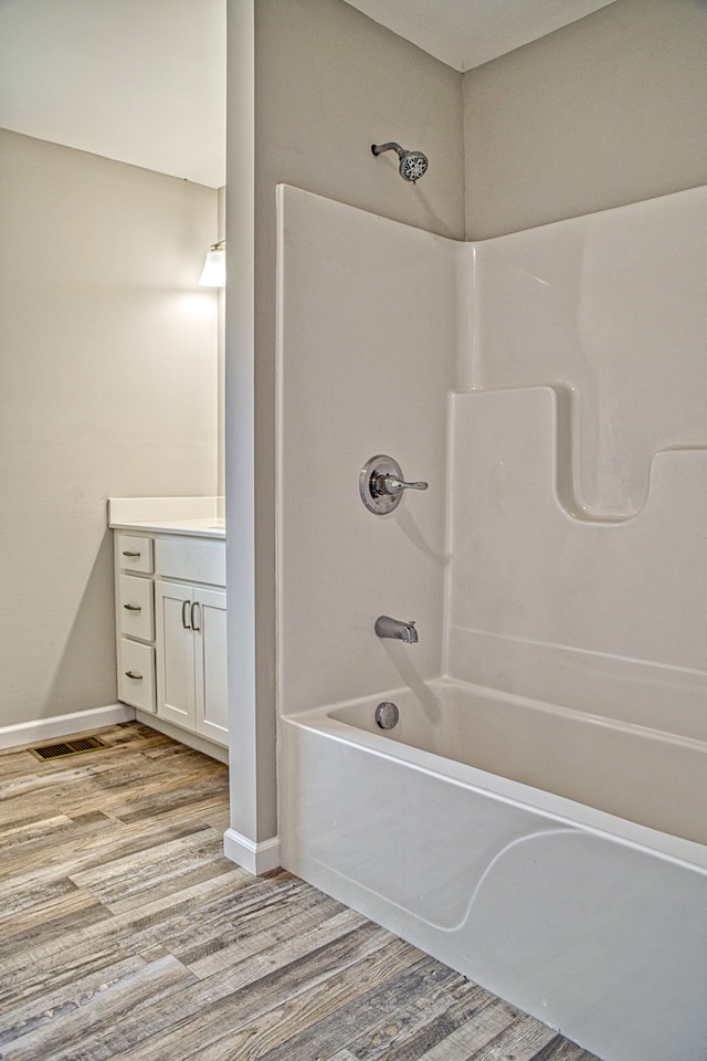 bathroom with vanity, hardwood / wood-style floors, and shower / bathtub combination