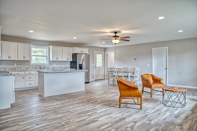 kitchen featuring stainless steel fridge with ice dispenser, a wealth of natural light, and white cabinets