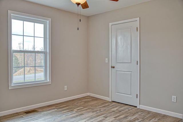 spare room with light hardwood / wood-style floors, a healthy amount of sunlight, and ceiling fan