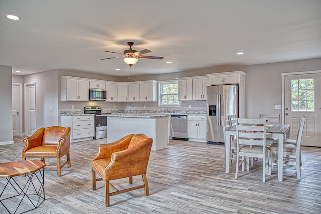 kitchen with appliances with stainless steel finishes, light hardwood / wood-style flooring, a healthy amount of sunlight, and white cabinets