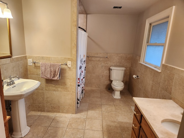 bathroom with tile walls, curtained shower, tile patterned floors, and toilet