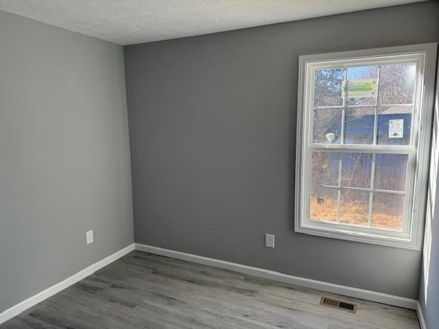 spare room featuring wood-type flooring and a textured ceiling