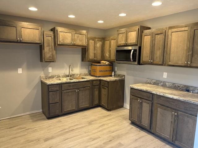 kitchen with light stone counters, sink, and light hardwood / wood-style floors