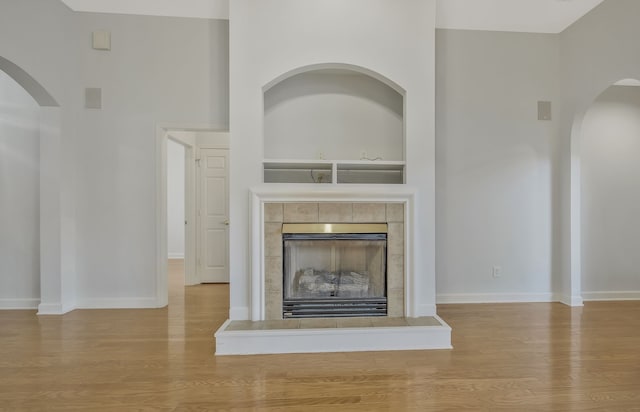 unfurnished living room with a tile fireplace and light hardwood / wood-style flooring