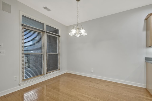 unfurnished dining area featuring a chandelier and light hardwood / wood-style flooring