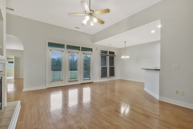 unfurnished living room featuring light hardwood / wood-style floors and ceiling fan with notable chandelier