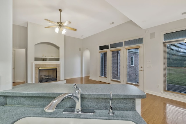 kitchen featuring light hardwood / wood-style floors, sink, ceiling fan, built in features, and a tile fireplace