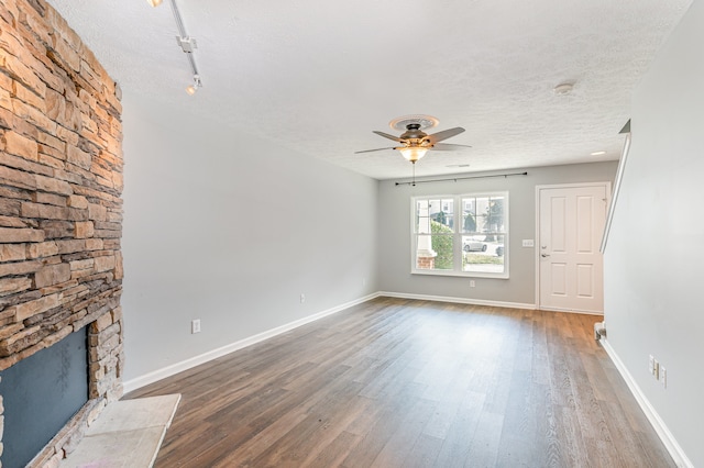 unfurnished living room featuring hardwood / wood-style floors, a textured ceiling, a fireplace, and ceiling fan