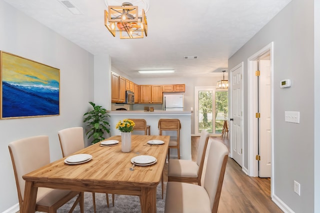 dining room with light hardwood / wood-style flooring and a notable chandelier