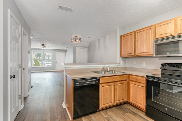 kitchen with kitchen peninsula, a textured ceiling, light hardwood / wood-style flooring, black appliances, and sink