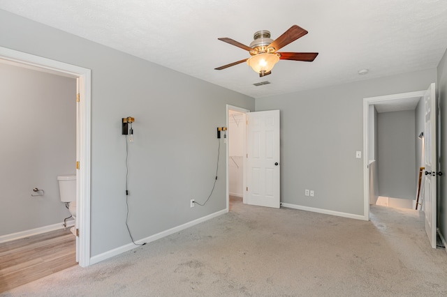 unfurnished bedroom featuring light carpet, ensuite bath, and ceiling fan