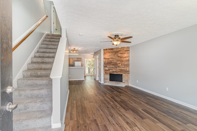 unfurnished living room with ceiling fan, a textured ceiling, dark hardwood / wood-style flooring, and a fireplace