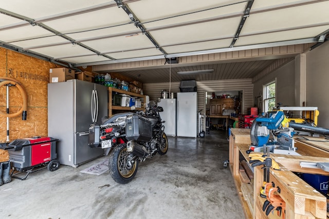 garage featuring white refrigerator and stainless steel fridge