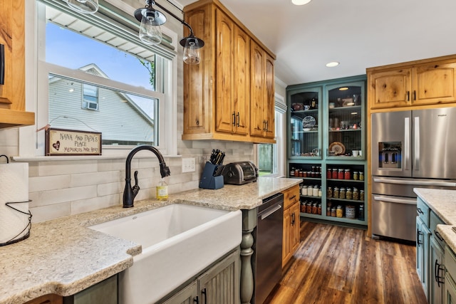 kitchen with dark hardwood / wood-style floors, light stone countertops, stainless steel appliances, and sink