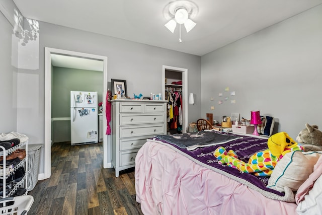 bedroom featuring ceiling fan, a walk in closet, dark hardwood / wood-style floors, a closet, and white refrigerator