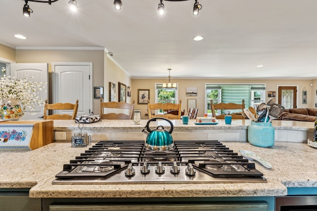 kitchen featuring ornamental molding, stainless steel gas stovetop, light stone counters, and decorative light fixtures