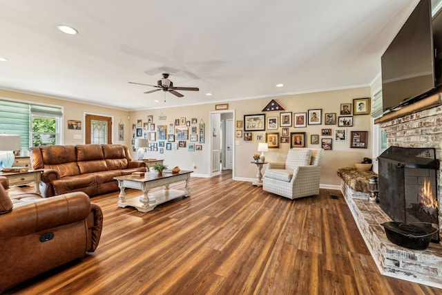 living room with ornamental molding, wood-type flooring, a fireplace, and ceiling fan