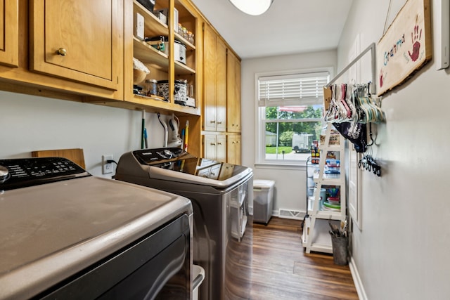 clothes washing area with independent washer and dryer, dark hardwood / wood-style floors, and cabinets