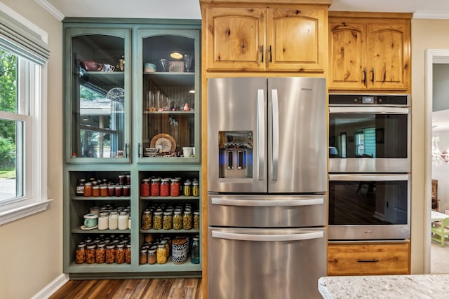 kitchen featuring dark wood-type flooring, light stone counters, appliances with stainless steel finishes, and ornamental molding