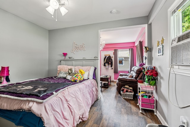 bedroom featuring multiple windows, ceiling fan with notable chandelier, and dark hardwood / wood-style flooring