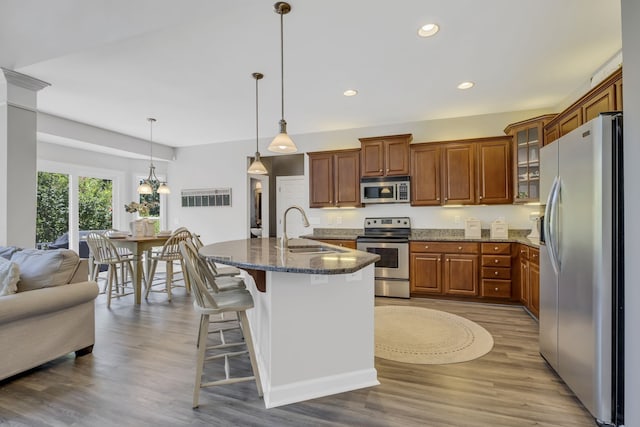 kitchen featuring a breakfast bar, light wood-type flooring, stainless steel appliances, sink, and decorative light fixtures