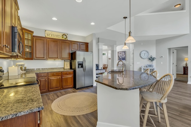 kitchen featuring appliances with stainless steel finishes, sink, an island with sink, decorative light fixtures, and dark hardwood / wood-style floors