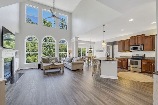 kitchen with a kitchen breakfast bar, stainless steel appliances, a center island with sink, and dark hardwood / wood-style flooring