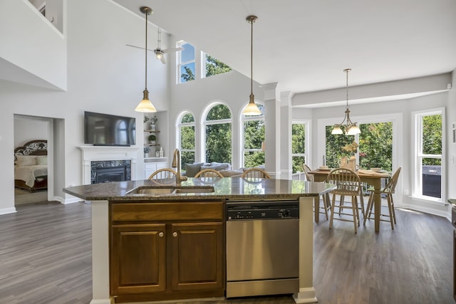 kitchen with dishwasher, dark hardwood / wood-style floors, dark stone countertops, sink, and ceiling fan with notable chandelier