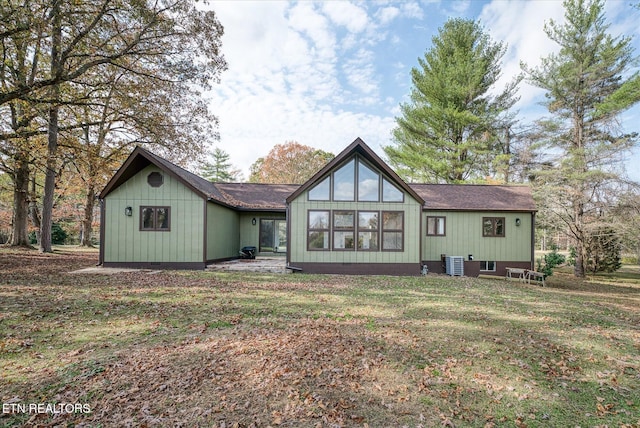 rear view of property with central air condition unit and a lawn