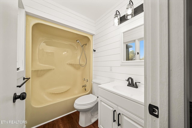 full bathroom featuring wood walls,  shower combination, toilet, vanity, and hardwood / wood-style flooring