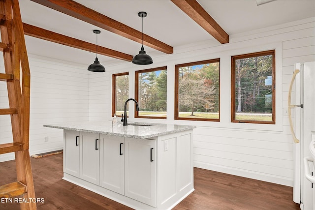 kitchen featuring a center island with sink, sink, pendant lighting, white cabinetry, and light stone counters