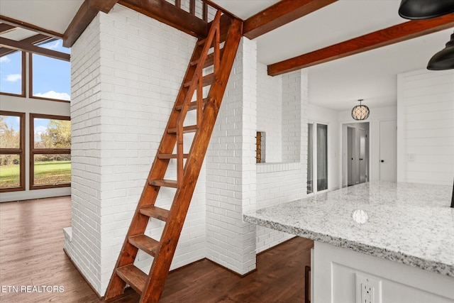 stairway featuring hardwood / wood-style flooring and brick wall