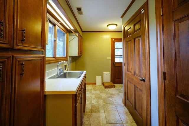 kitchen with ornamental molding, sink, and light tile patterned floors